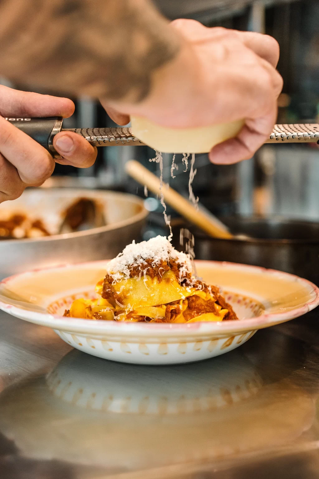 Parmesan being grated over a plate of fresh fettuccine pasta
