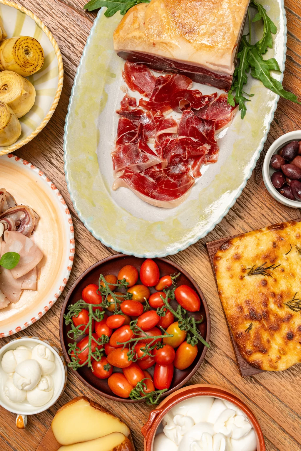 Overhead antipasti board with prosciutto, cherry tomatoes and focaccia at Zia Tina