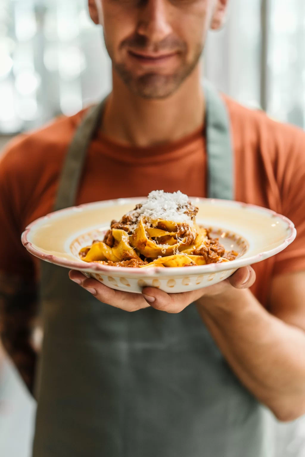 Chef sorridente mostra un piatto di pasta fresca in un ristorante italiano bali