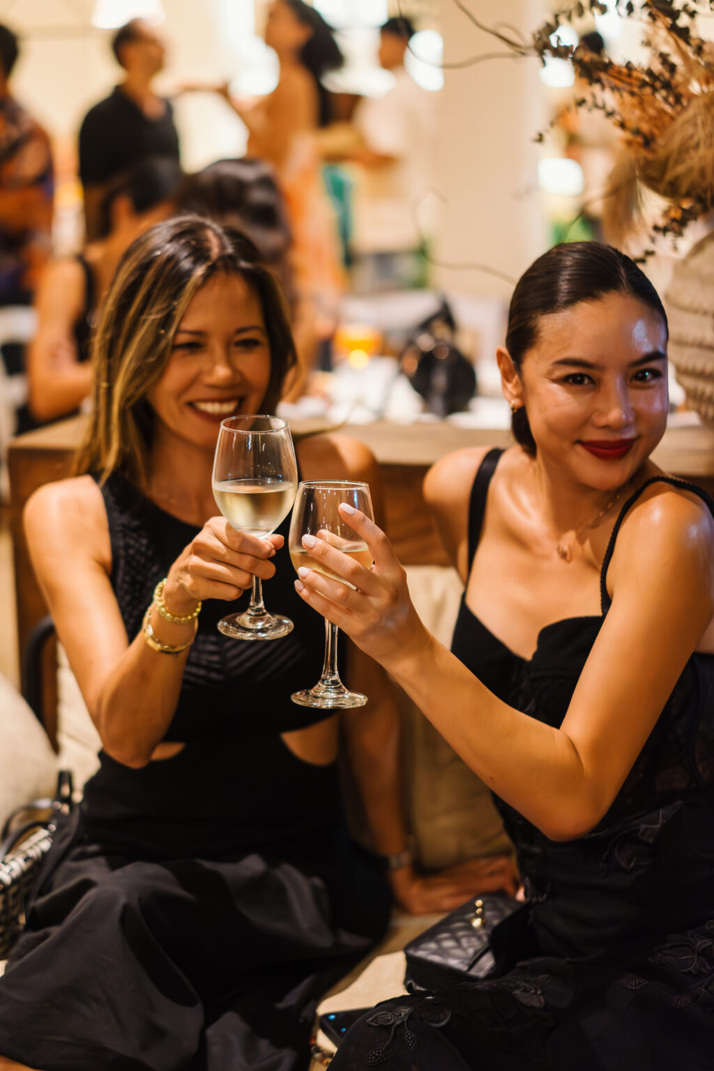 Two friends toasting with white wine during an anniversary dinner Bali evening