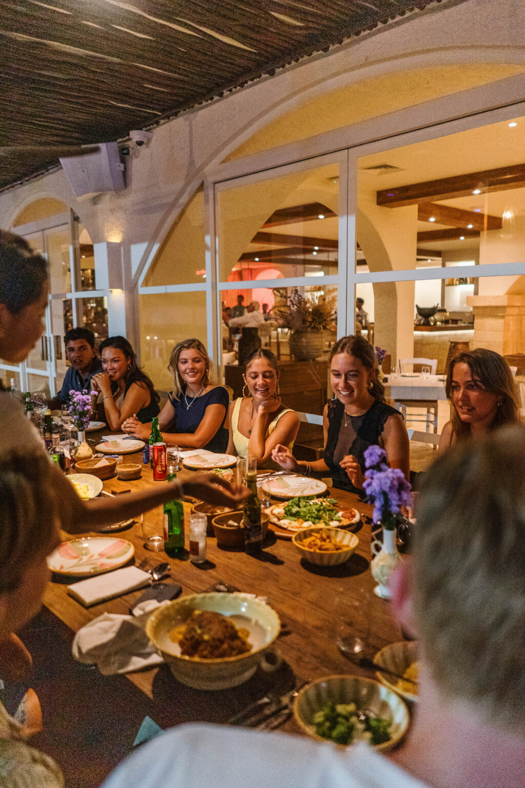 Big group sharing dinner at a long table on the terrace
