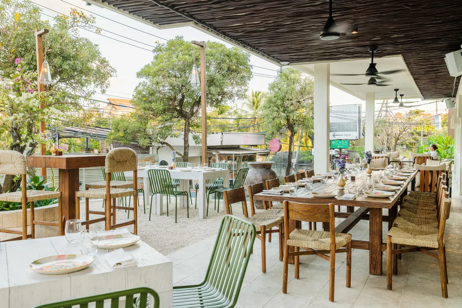 Outdoor terrace with long wooden tables and greenery for evening dinner